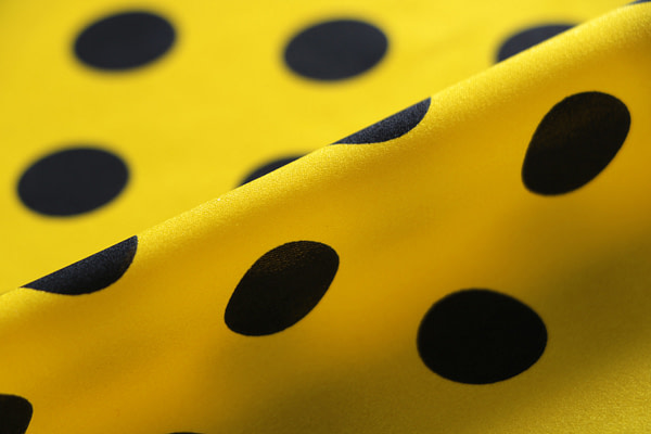 Silk satin fabric printed with a dark blue maxi polka dot motif on a yellow background | new tess